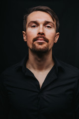 Obraz premium Handsome man. Photo in a photo studio on a black background. A young man expresses his emotions with expressions, gesticulation and attitude.