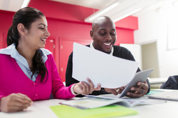 Smiling community college students with paperwork and digital tablet