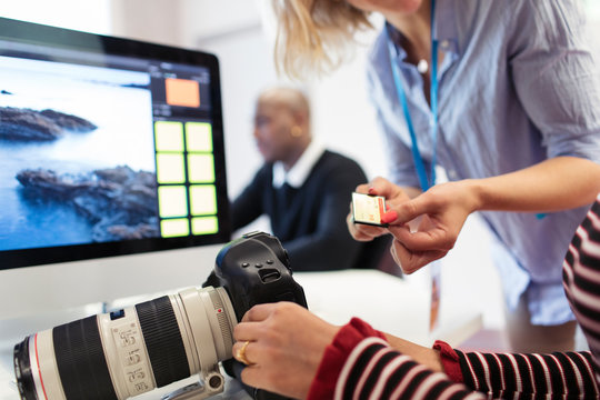 Photography Students With Digital Camera And Memory Card At Computer