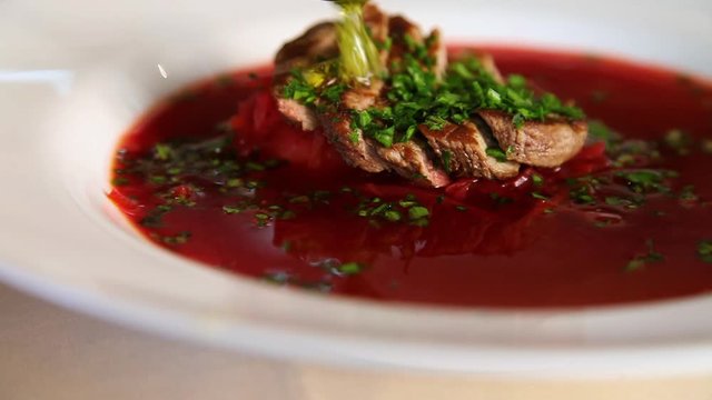 Close-up of the process of watering with garlic oil borscht with meat and finely sliced herbs.Borsch.