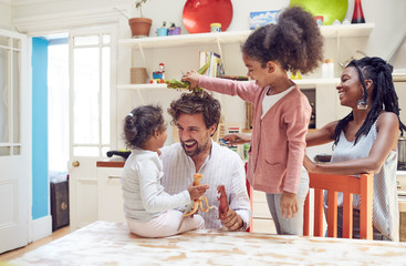 Young family playing with toy dinosaurs in kitchen