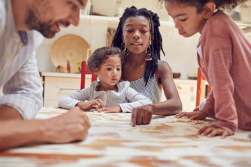 Young family playing scrabble word game at table