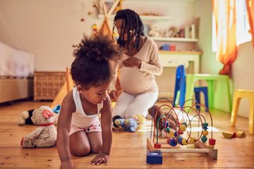 Pregnant mother and daughter playing with toys