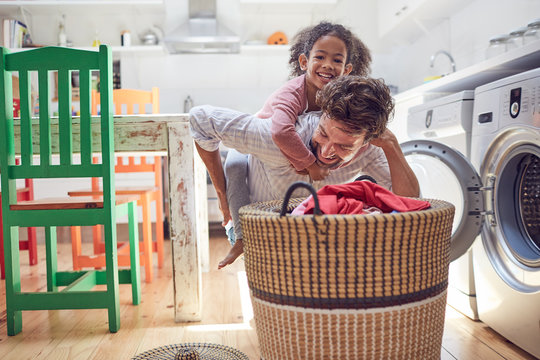 Playful Father And Daughter Doing Laundry