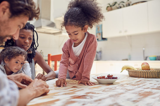 Young family playing scrabble word game at table