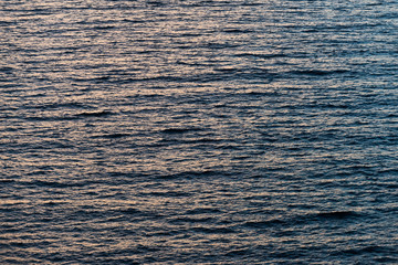 Calm sea with nice reflection of yellow sky and rippled surface.