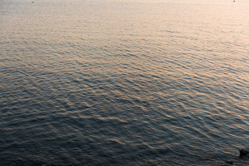 Calm smooth sea with nice reflection of yellow sky.