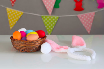 Bright Easter eggs made of plastic, rabbit ears on a white table. Happy Easter! Decorating the kitchen for Easter on a Sunny day.