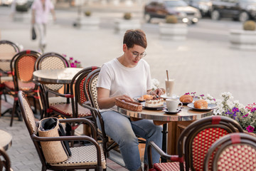 Sad girl in a cafe. European woman with short hair in Paris drinks hot drinks and eats croissants