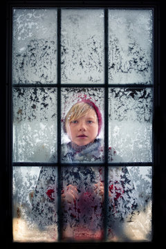 Boy looking through a frosty window, USA