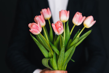 bouquet of pink tulips in men's hands in a blue suit