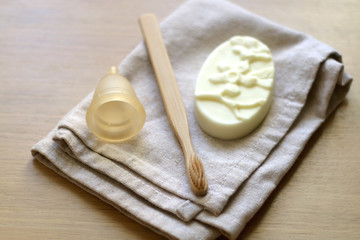 Linen cloth, soap, bamboo toothbrush and menstrual cup. Zero waste bathroom products. Selective focus.