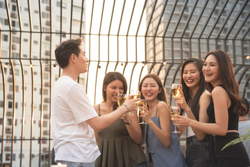 Group of asian multiple gender holding glass of wine chat together with friends while celebrating dance party on outdoor rooftop nightclub,leisure lifestyle of young friendship enjoyment concept.