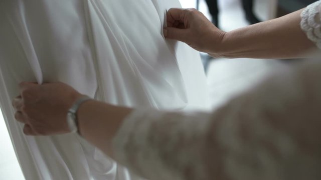 witness adjusting Bride wedding dress