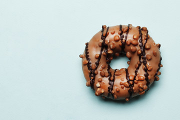 Sweet donut with chocolate icing on a blue background