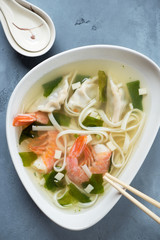 Bowl of wonton noodle soup with shrimps, vertical shot, top view, close-up