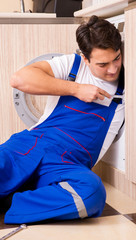 Obraz premium Repairman repairing washing machine at kitchen