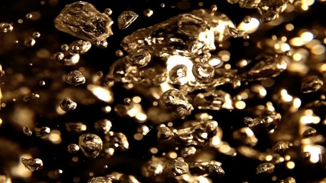 Slow Motion Video: The chaotic slow motion of air bubbles inside boiling water. Abstract golden background with moving and vibrating volume bubbles, blurry spots and bright highlights