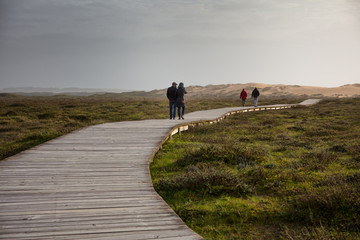 Corrubedo Natural Park, Galicia, Spain: People walking along the wooden path that gives access to the large dune, the main attraction of the park.