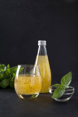 Tropical cocktail with basil seeds and orange juice in glass on black. Close up.