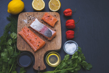 pepper, salted slices of salmon, greens and salt lie on a table