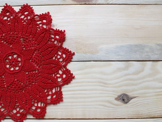 Red crocheted doily on a light background. Free space for an inscription. Handwork and needlework.