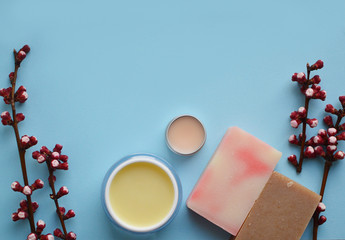 face cream, lip balm, soap on a blue background with spring flowers.Space for a text. Copy space....