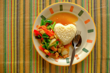 Street food stir fry vegetable with steamed rice in heart shape, serving on colorful table
