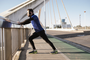 man stretching on a bridge railing. sport concept © ImagineStock