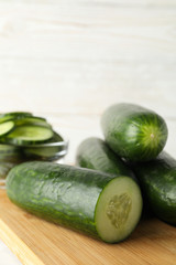 Board with cucumbers on wooden background, close up