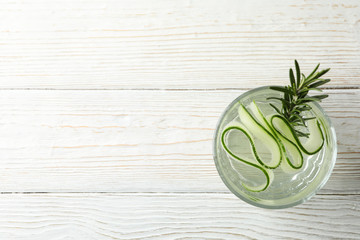 Glass with infused cucumber water on wooden background, top view