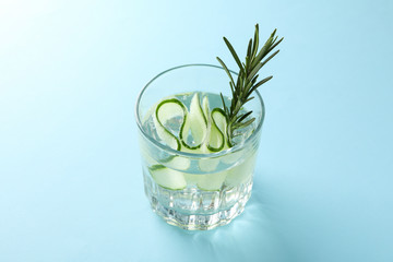 Glass with infused cucumber water on blue background, close up