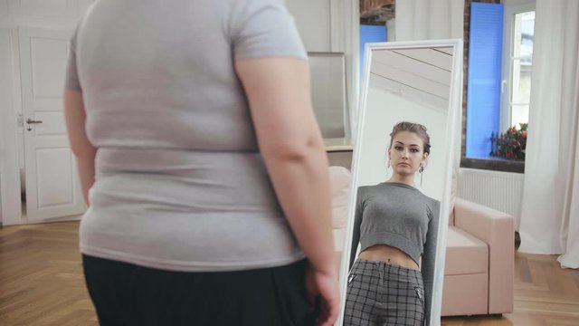 Fat woman sees herself in the mirror as a slim girl