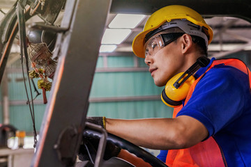 A man with yellow safety helmet and goggles driving a forklift or reach  truck  at the logistics...