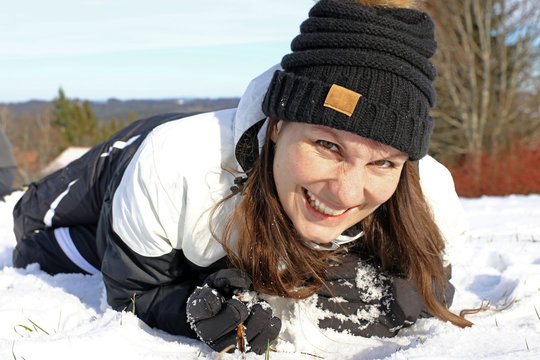Eine junge Frau hat Spa&szlig; im Schnee. Eine junge Frau liegt lachend im Schnee