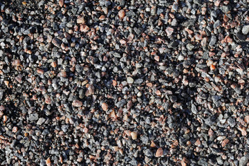 Small colorful rocks mostly brown and grey colors. Spa like calm, relaxing background texture. Photographed in Finland during a sunny spring day. Beautiful natural rock pattern. Closeup color photo.