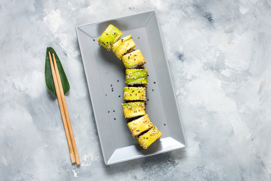 Green dragon sushi roll with eel, avocado, cucumber on concrete table. Traditional asian rice healthy seafood.