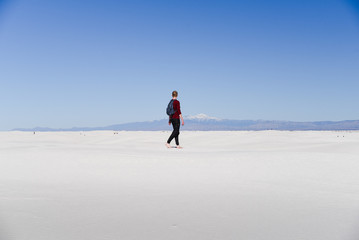 A man walking across sand dunes. 