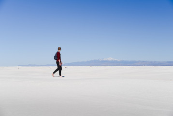 A man walking across sand dunes. 