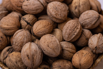  Walnuts on a white background in a small wicker basket. A lot of walnuts. Close-up