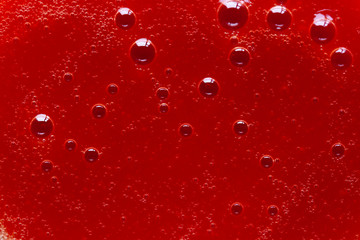 Fresh organic tomatoes juice with bubbles macro close up. Red liquid texture