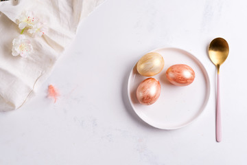 Easter table setting from above. Elegant empty plate, cutlery, napkin and golden eggs on stone