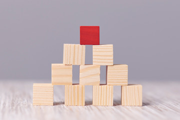 red wood cube block on top pyramid, for create icon symbol to success concept. hink outside the box. Dare to be different.