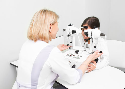 Feale doctor checking eyesight of a girl on modern equipment in clinic. Diagnosis and treatment of strabismus