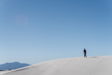 Fototapeta na wymiar A man walking in the distance at White Sands National Park in Alamogordo, New Mexico. 