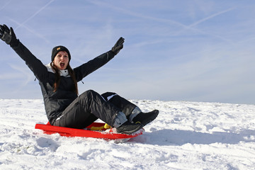 Eine junge Frau hat im Winter Spaß beim Schlittenfahren