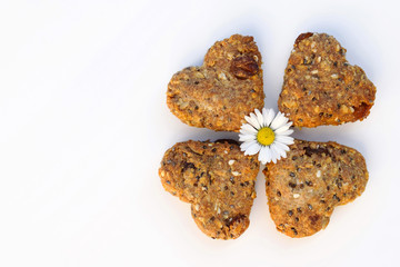 Homemade whole grain cookies with several kinds of seeds, raisins, ground nuts, oatmeal. Romantic concept, decorated with Daisy flower