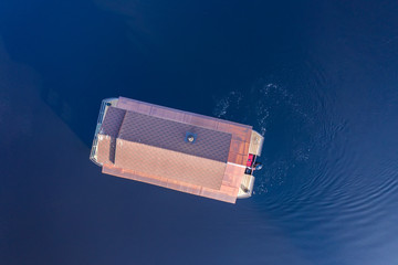 Fototapeta premium Aerial view of a house-bath boat running along the surface of a lake in Karelia