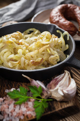 Fried onion in a cast iron skillet standing on a wooden countertop.