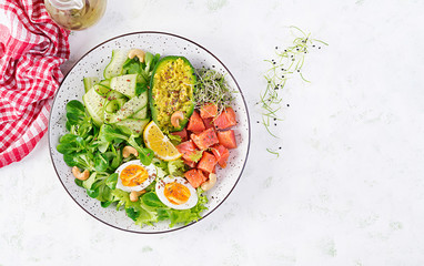 Fototapeta na wymiar Ketogenic diet breakfast. Salt salmon salad with greens, cucumbers, eggs and avocado. Keto/paleo lunch. Top view, overhead